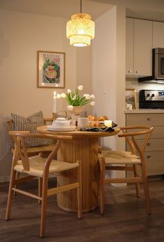 a dining room table with chairs and a vase on top of it in front of a microwave