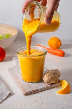 someone pouring orange juice into a small jar