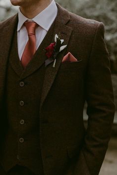 a man in a suit with a red tie and flower boutonniere on his lapel