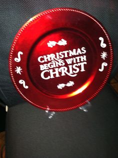 a red plate with the words christmas begins with christ on it sitting on a chair