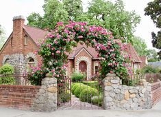 a brick house with pink flowers on the front gate