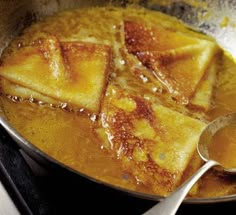 some food that is in a pan on the stove and ready to be eaten with spoons