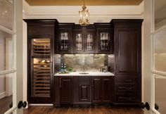 a kitchen with dark wood cabinets and marble counter tops, wine racks in the back