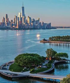 an island in the middle of water with a city skyline in the background at dusk