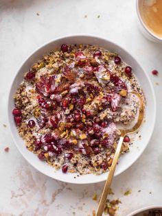 a bowl filled with oatmeal and cranberries next to two cups of coffee