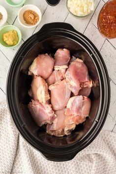 raw chicken in a slow cooker surrounded by other ingredients