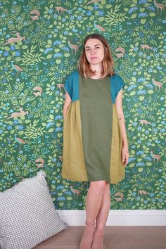 a woman standing in front of a green wallpaper