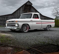 an old white truck parked in front of a barn