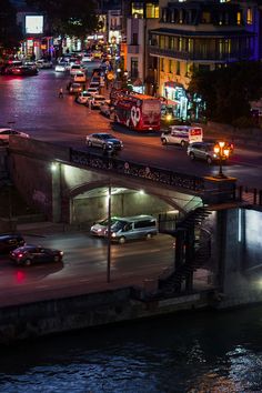 cars are driving down the street in front of a bridge at night with lights on