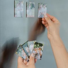 a person holding up four polaroid photos in front of a refrigerator freezer with magnets on it