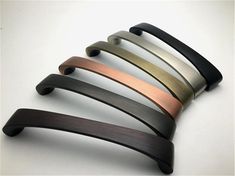 four different colors of handles on a white surface with one black, one gold and one silver