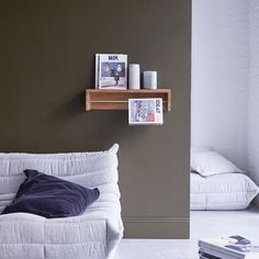 a white couch sitting next to a wall with pictures on top of the shelf above it