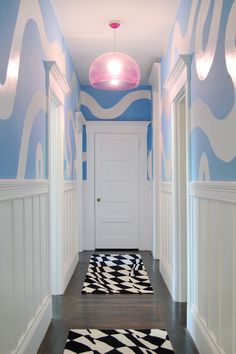 a hallway painted in blue and white with black and white rugs on the floor