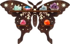 a wooden butterfly shaped shelf with crystals on it's wings and two different colored stones