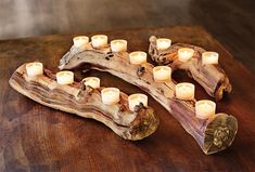 candles are arranged on a piece of driftwood that is sitting on a table top