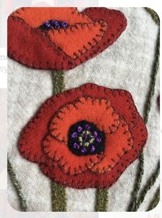 two red flowers with purple centers on a white background and text that reads, felted poppies