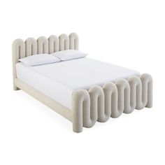 an upholstered bed with white sheets and pillows