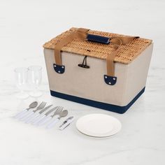 a picnic basket with utensils and silverware sits on a marble countertop