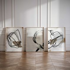 three framed art pieces sitting on top of a wooden floor