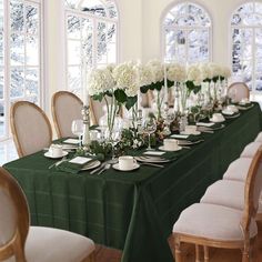 a long table is set with white flowers and place settings for formal dinnereons