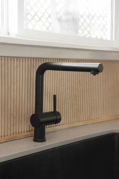 a kitchen sink with a black faucet next to a window