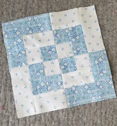 a blue and white patchwork quilt laying on the ground