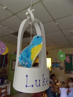 a blue and yellow bird hanging from the ceiling in a room with other children around