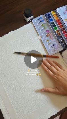 a person is painting with watercolors on a paper and holding a paintbrush