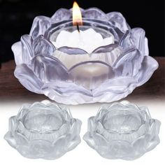 a candle that is sitting in front of a glass bowl with two flowers on it