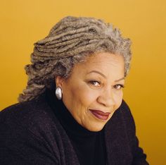 an older woman with dreadlocks on her head and wearing a black sweater, smiling