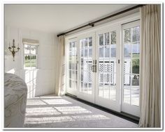 the sun is shining through the windows in this room with white walls and curtains on either side of the glass doors