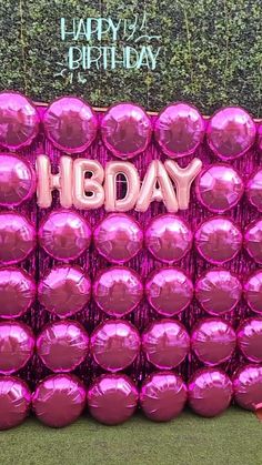 pink balloons with the word hbday written on them in front of a green wall