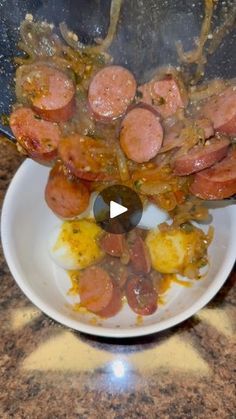 a white bowl filled with cooked sausages and potatoes on top of a countertop