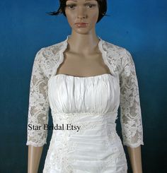 a mannequin wearing a white dress and jacket with lace on the sleeves,