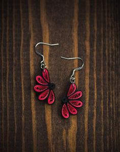 red and black earrings on a wooden surface