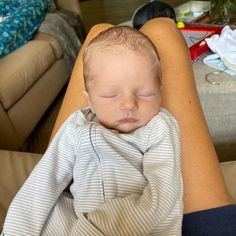 a woman holding a baby in her arms while laying on the floor next to a couch