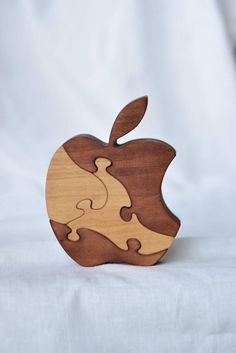 an apple shaped wooden puzzle sitting on top of a white sheet