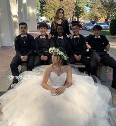 a group of people sitting on top of a wooden bench wearing formal wear and flowers in their hair