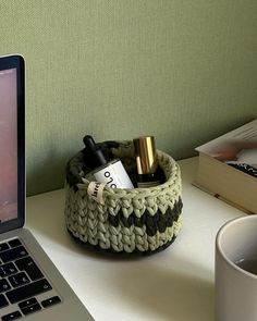 an open laptop computer sitting on top of a white desk next to a basket filled with wine bottles