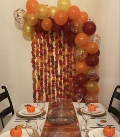 the table is set with plates, silverware and orange balloons on the wall behind it