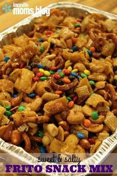 a tin pan filled with snack mix on top of a wooden table