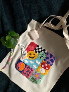 a white tote bag sitting on top of a bed next to a green plant