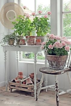 a white table topped with potted plants next to a window filled with pink flowers