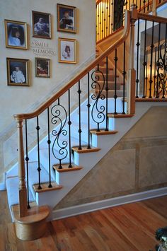 there is a stair case with pictures on the wall next to it and an iron handrail