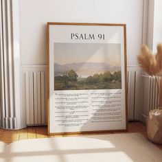 a framed poster on the floor next to a vase with some dry grass in it