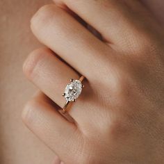 a woman's hand with a diamond ring on her left hand, showing the center stone