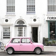 a pink car parked in front of a white building