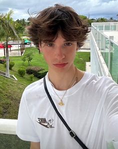 a young man taking a selfie in front of a green lawn and palm trees