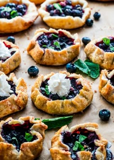 small pastries with blueberries and spinach are on a baking sheet, ready to be eaten