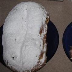 two blue plates topped with donuts covered in powdered sugar and one filled with frosting